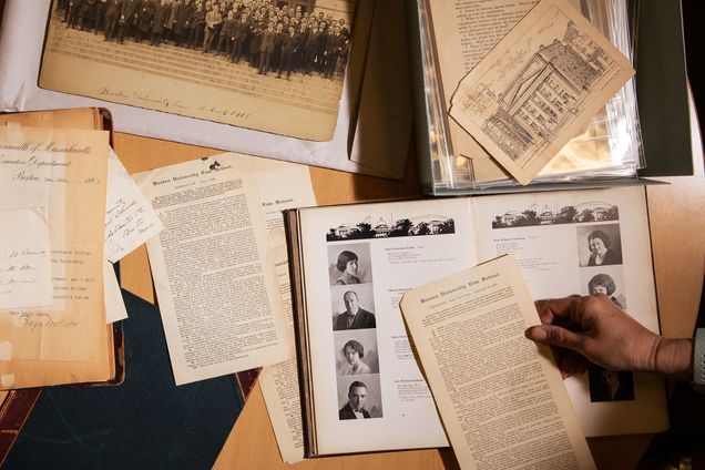 A group of documents from the BU Law archives, including an illustrated postcard of 11 Ashland Place, exams from the late 1800s, and a yearbook from 1922