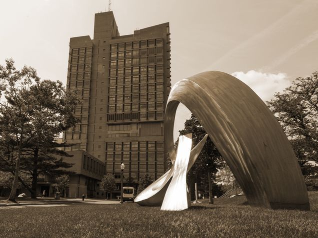 A sepia-toned photo of the BU Law tower with the BU beach and the whale sculpture in the foreground