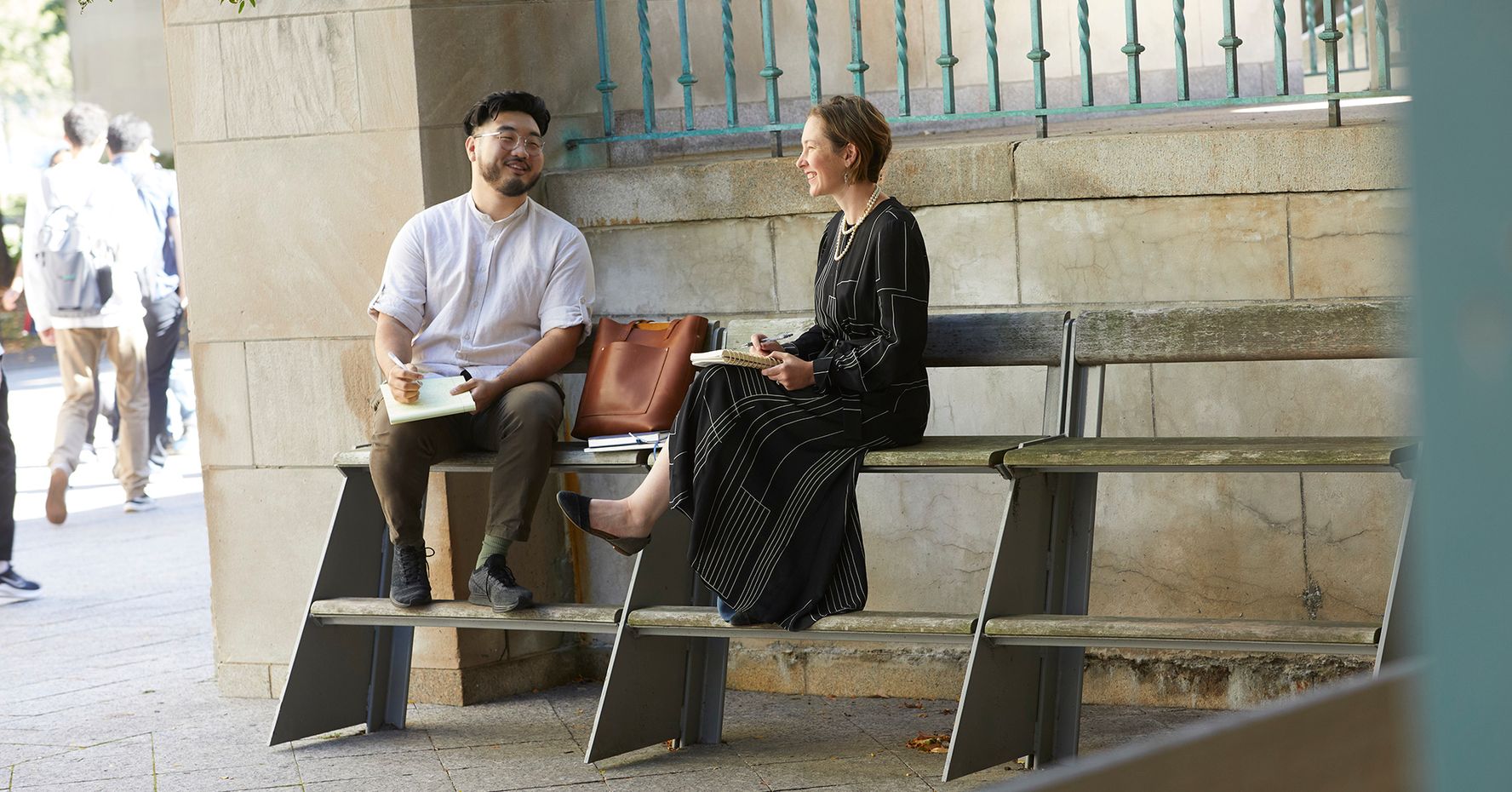 Julie Dahlstrom and James Cho ('22) sit on a bench outside the Law Tower.