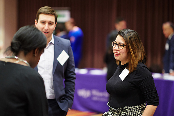 Three lawyers in business attire chat at a networking event.