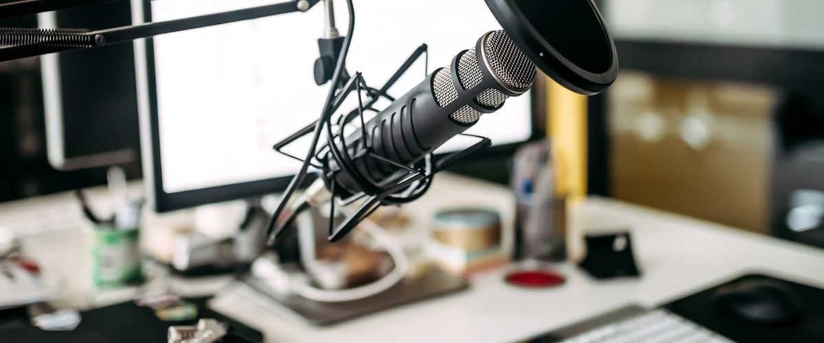 A microphone positioned in front of a computer in a recording studio