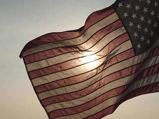 American USA flag waving in sunset outdoor background for honoring USA military