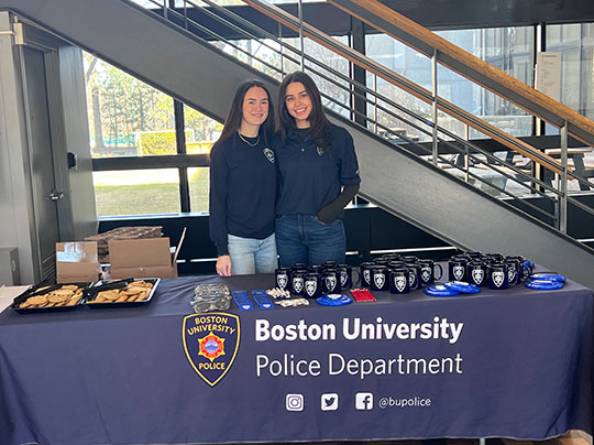 Celia “Cece” Carl poses behind a table with BUPD branding and merchandise