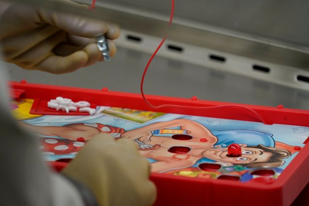 Closeup shot of gloved hands removing an object form the board game operation