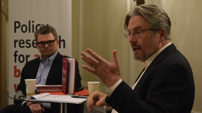 Kevin Gallagher sits in front of a GDP Center banner as Perry Mehrling emphatically addresses the crowd at his book talk.