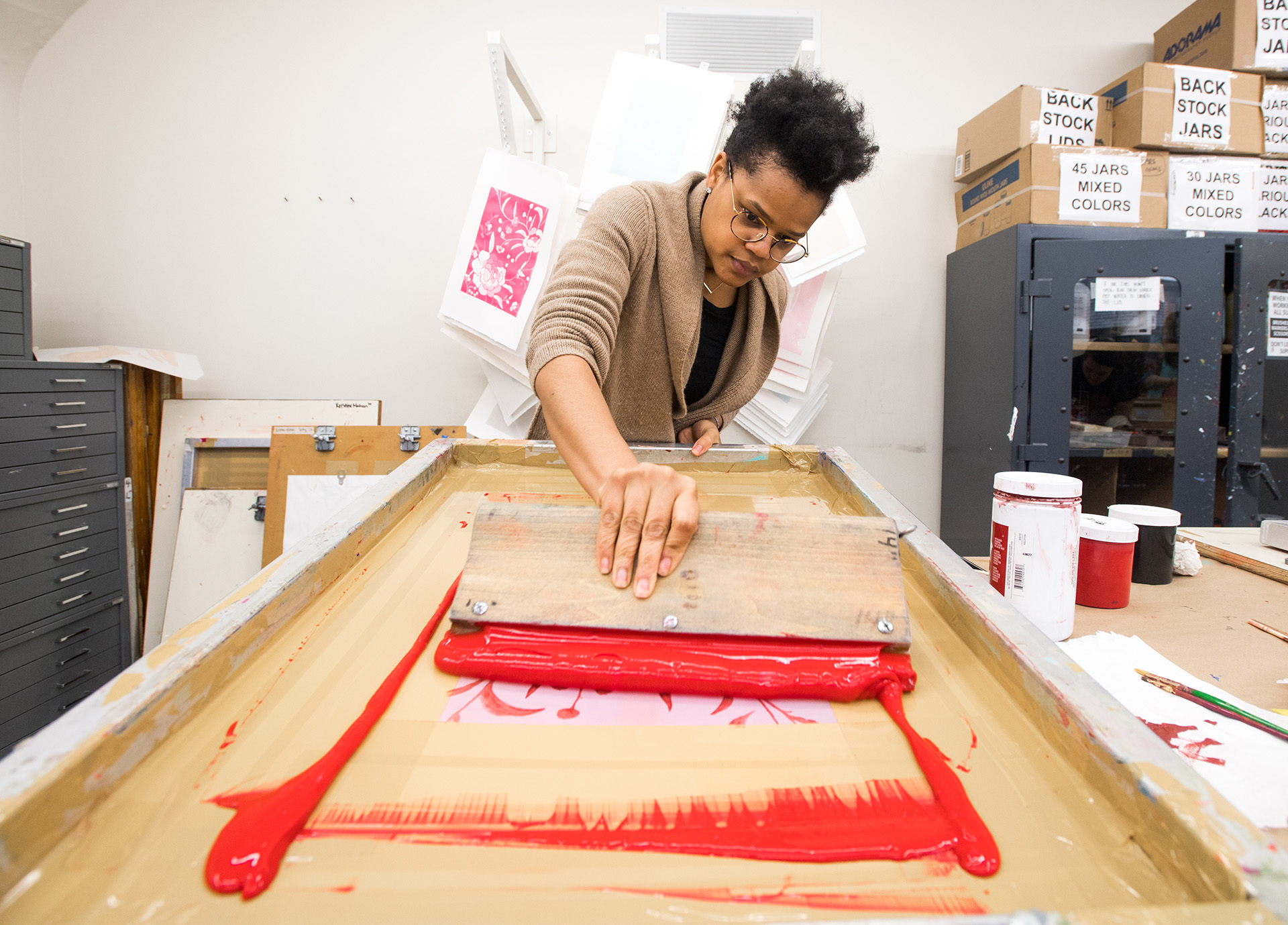 Alex Creamer (CFA'17) pulls paint across her screen in Silkscreen Printing class.