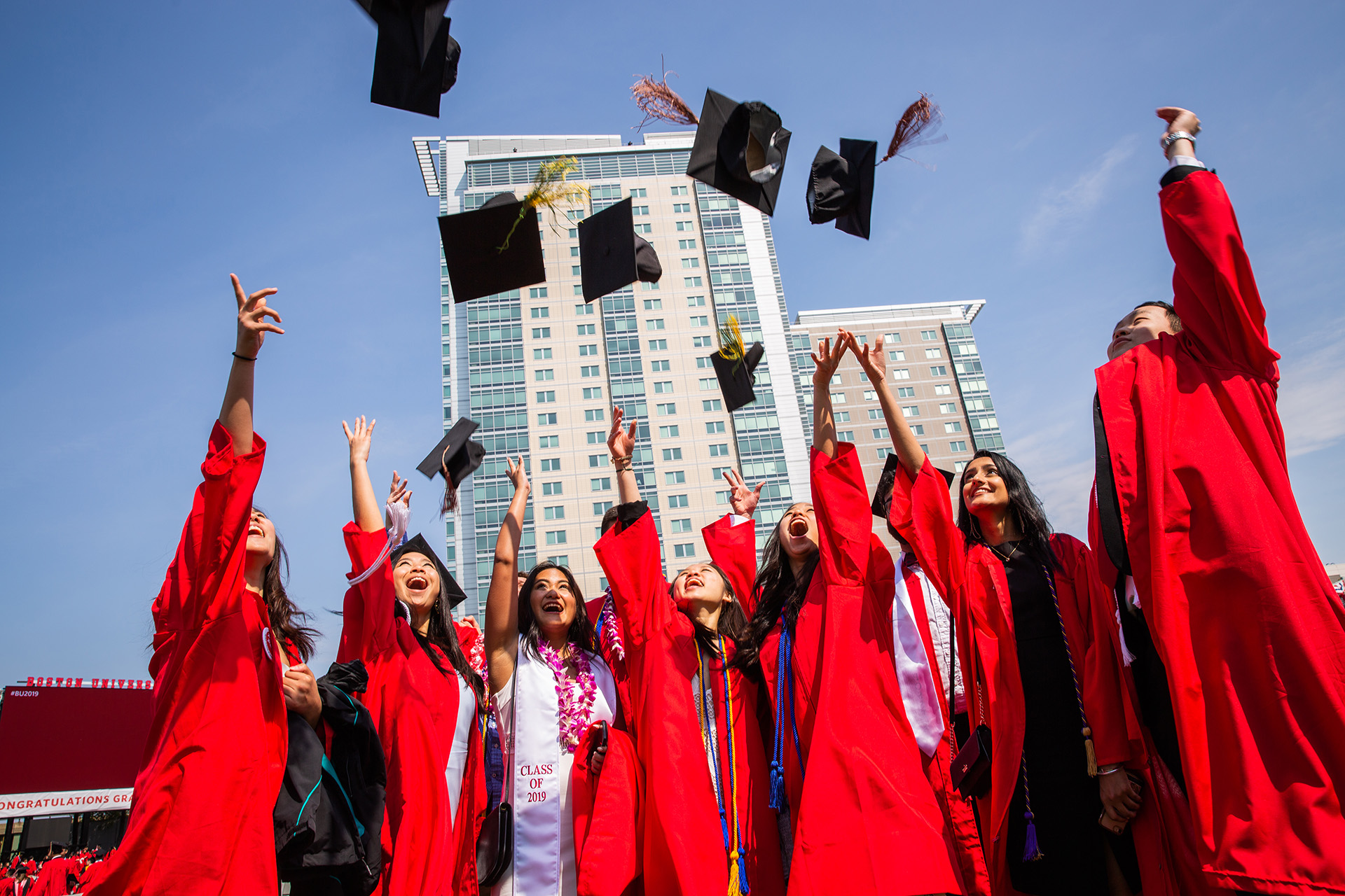 Students happily throwing their caps in the air at the 2019 Boston University Commencement on Nickerson Field.