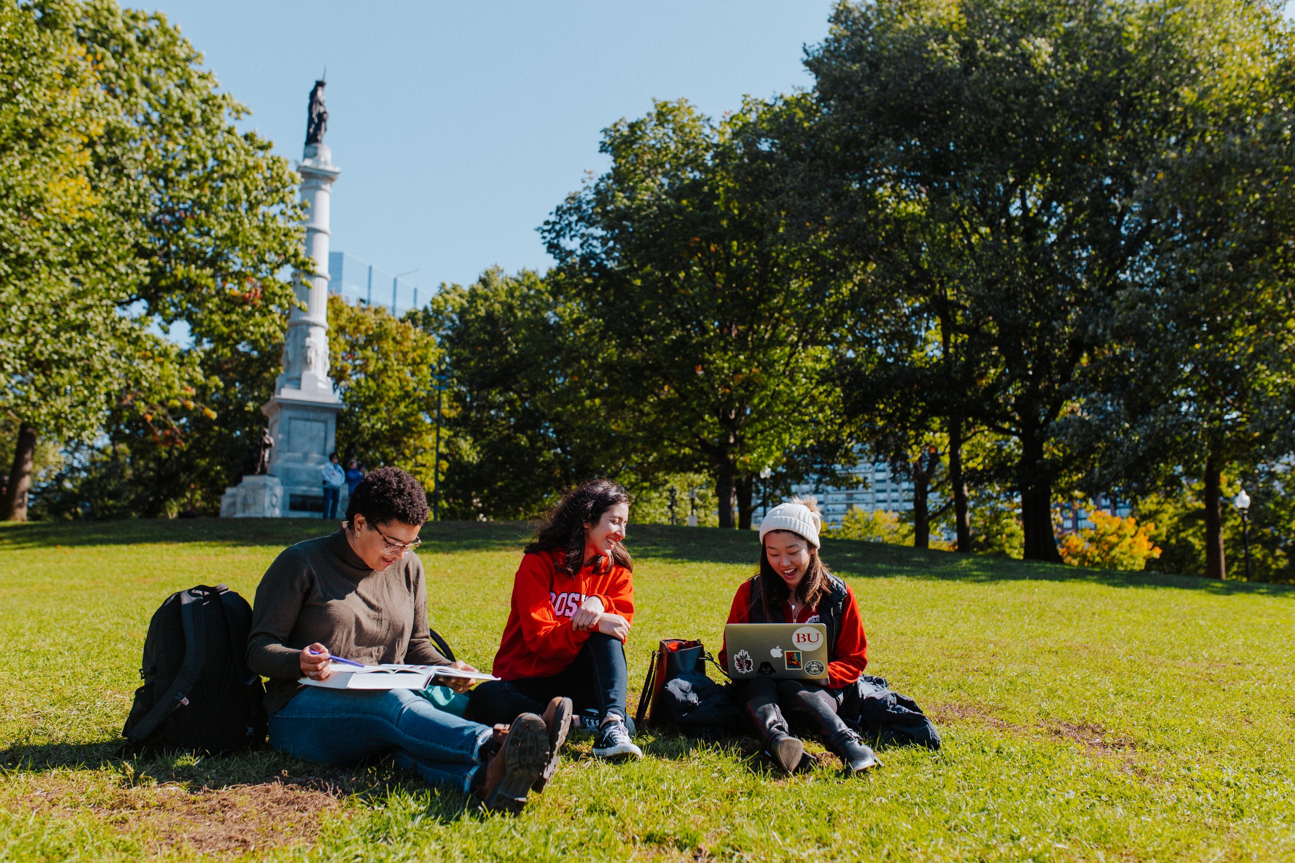 Three students sitting in a park.