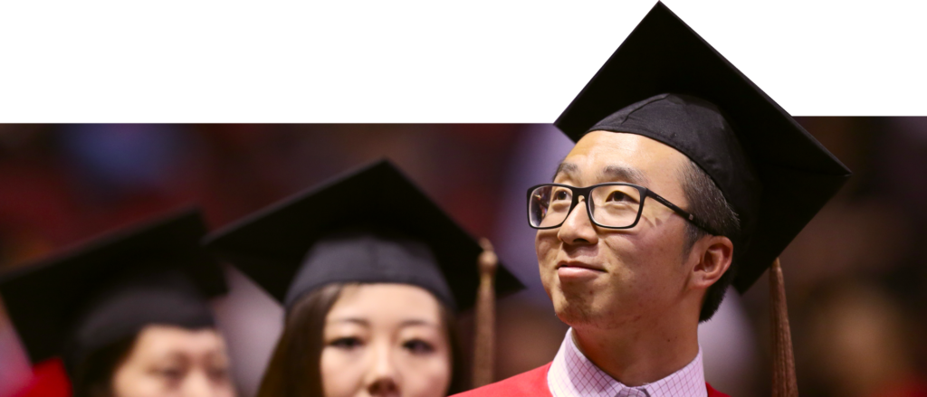 Male student with graduation cap looking proudly up at the stage