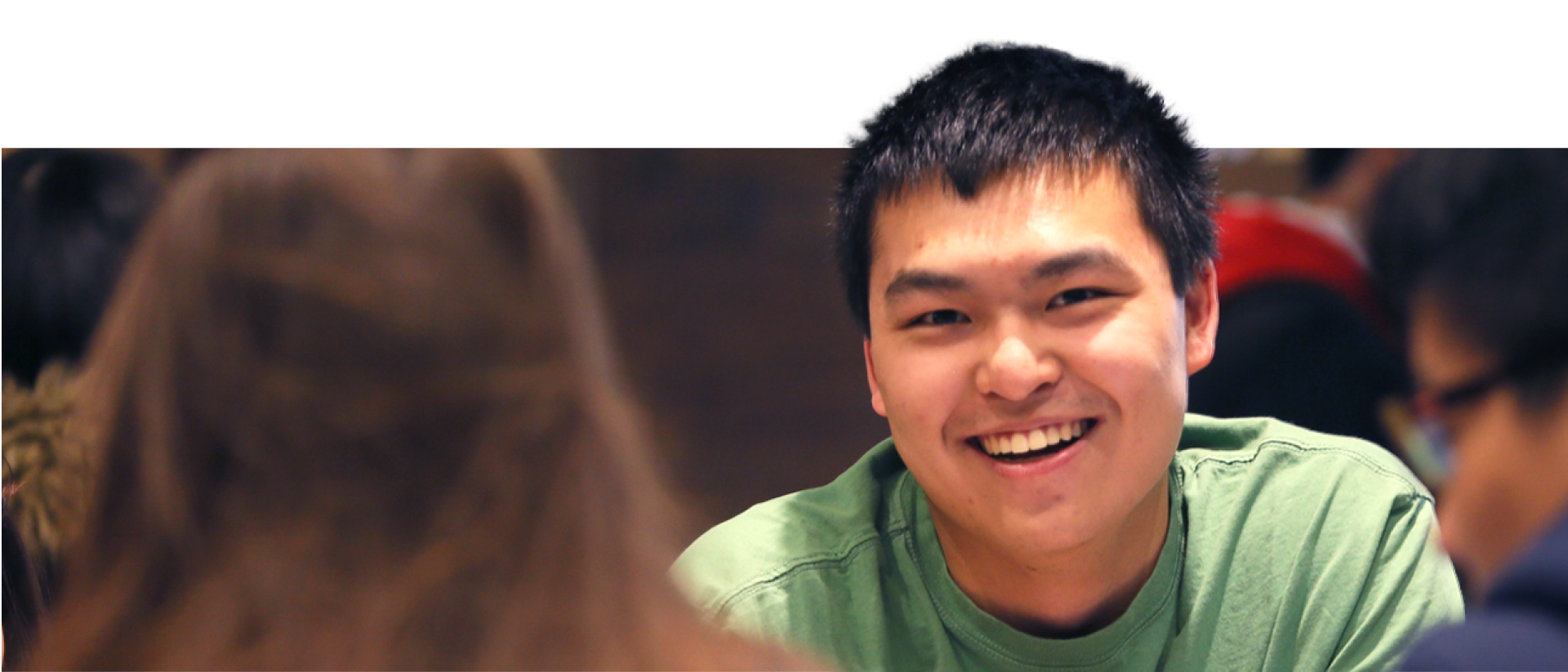 Student in green shirt smiling at camera