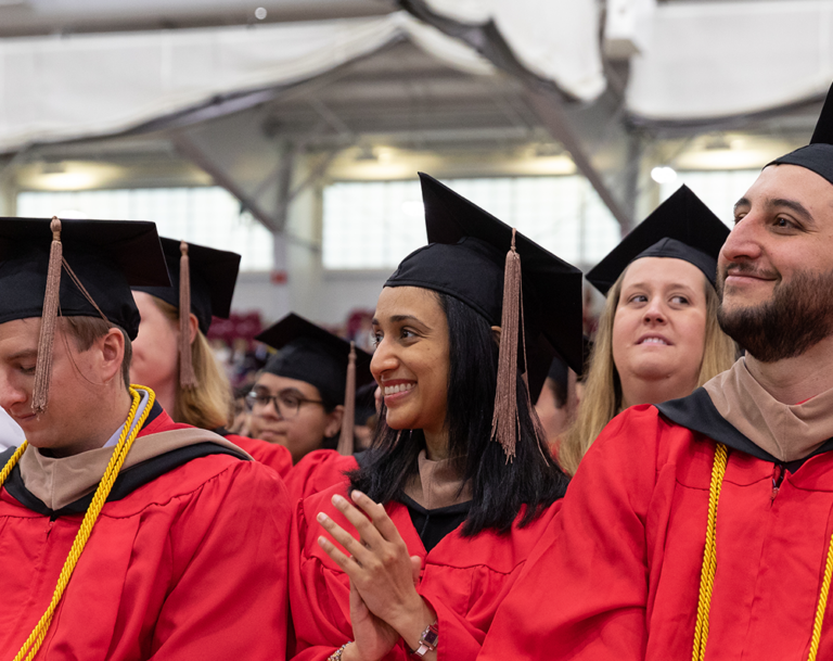 Students sitting in cap and gowns at commencement.