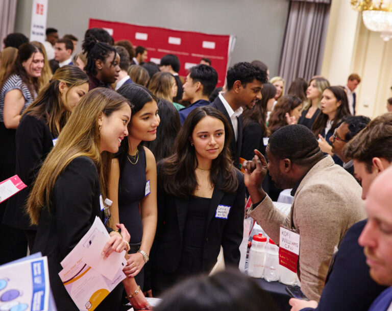 Students listening to a potential employer at a booth at a career fair.