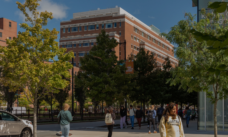 Students walking around BU campus with tall building in background