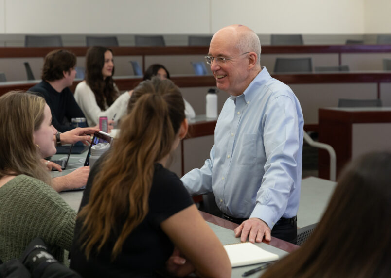 Male professor speaking to a group of seated students in a classroom