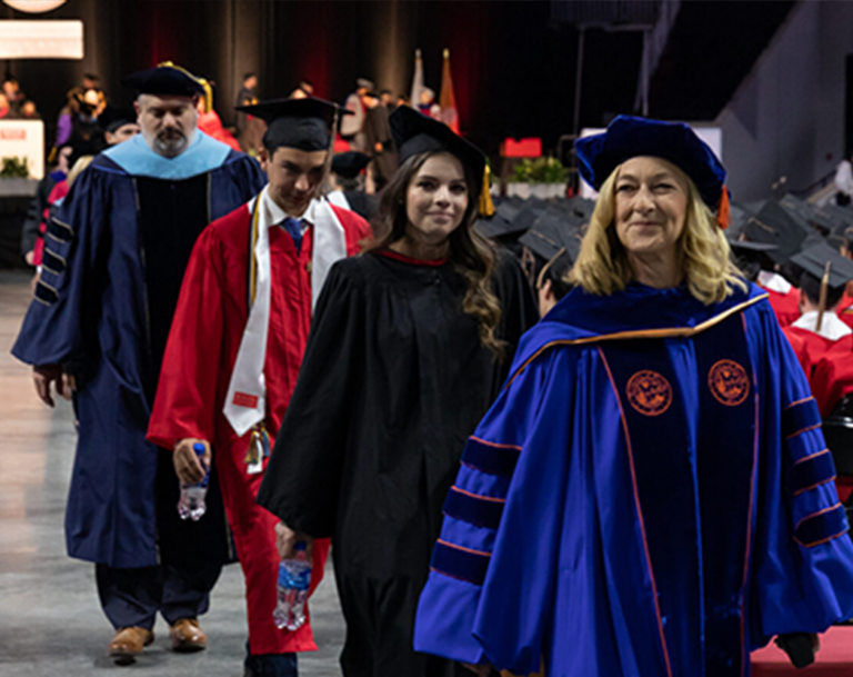 Dean Fournier leading a line of students across the floor at commencement