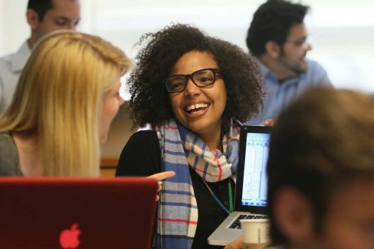 Two women students talk and laugh in a classroom