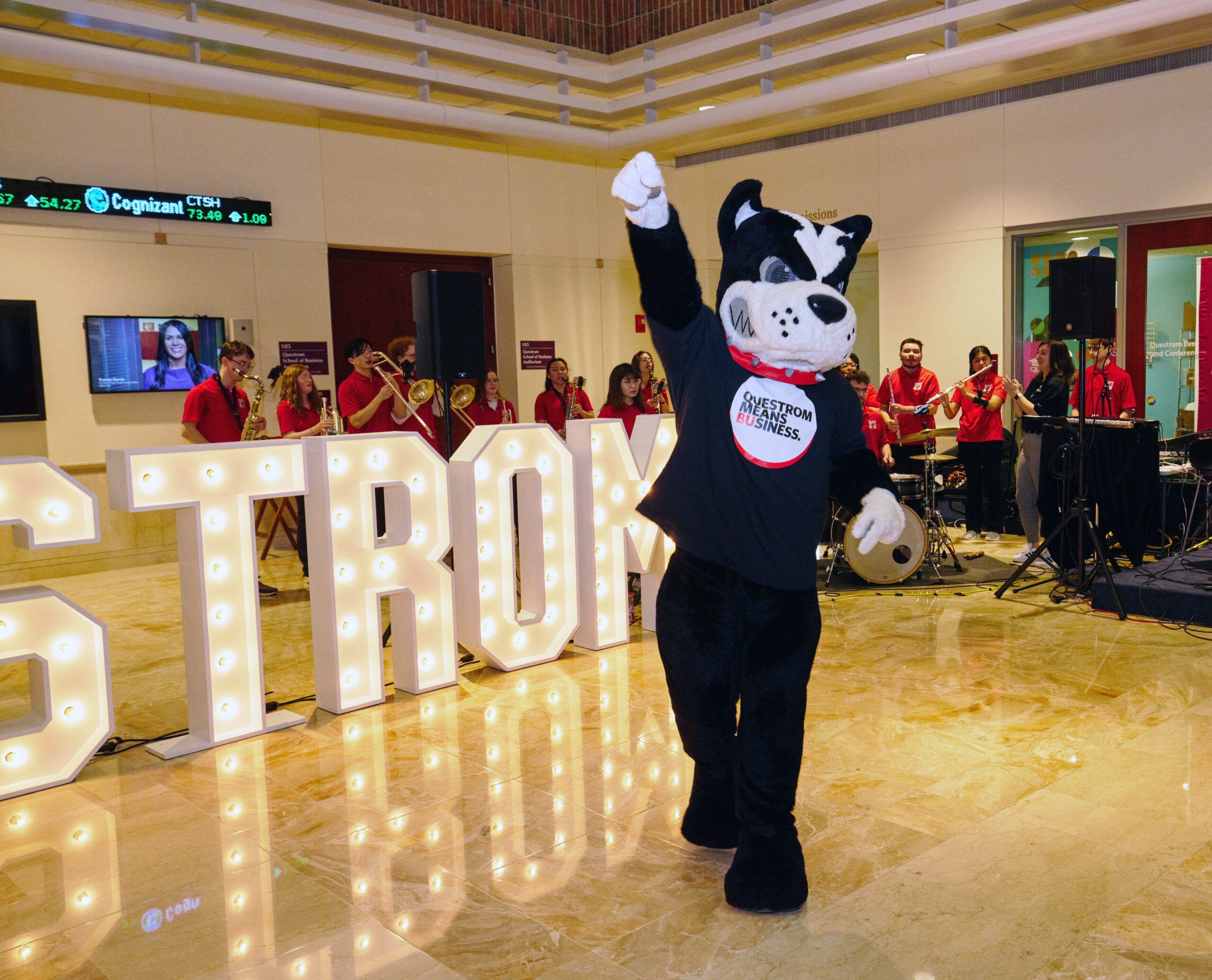 Rhett the Boston Terrier mascot poses in front of the Questrom Light up letters in the Atrium