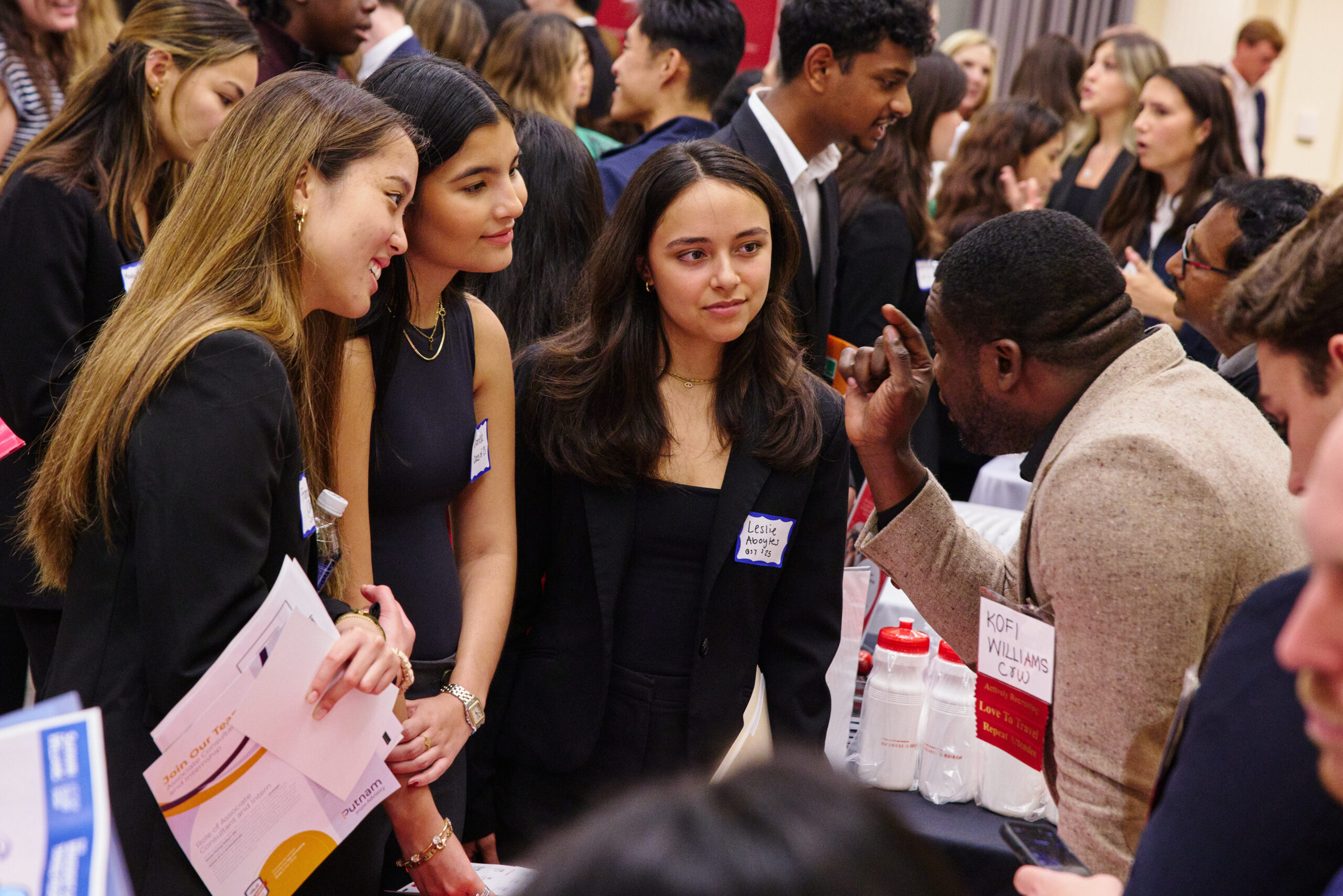 Students listening to a potential employer at a booth at a career fair.