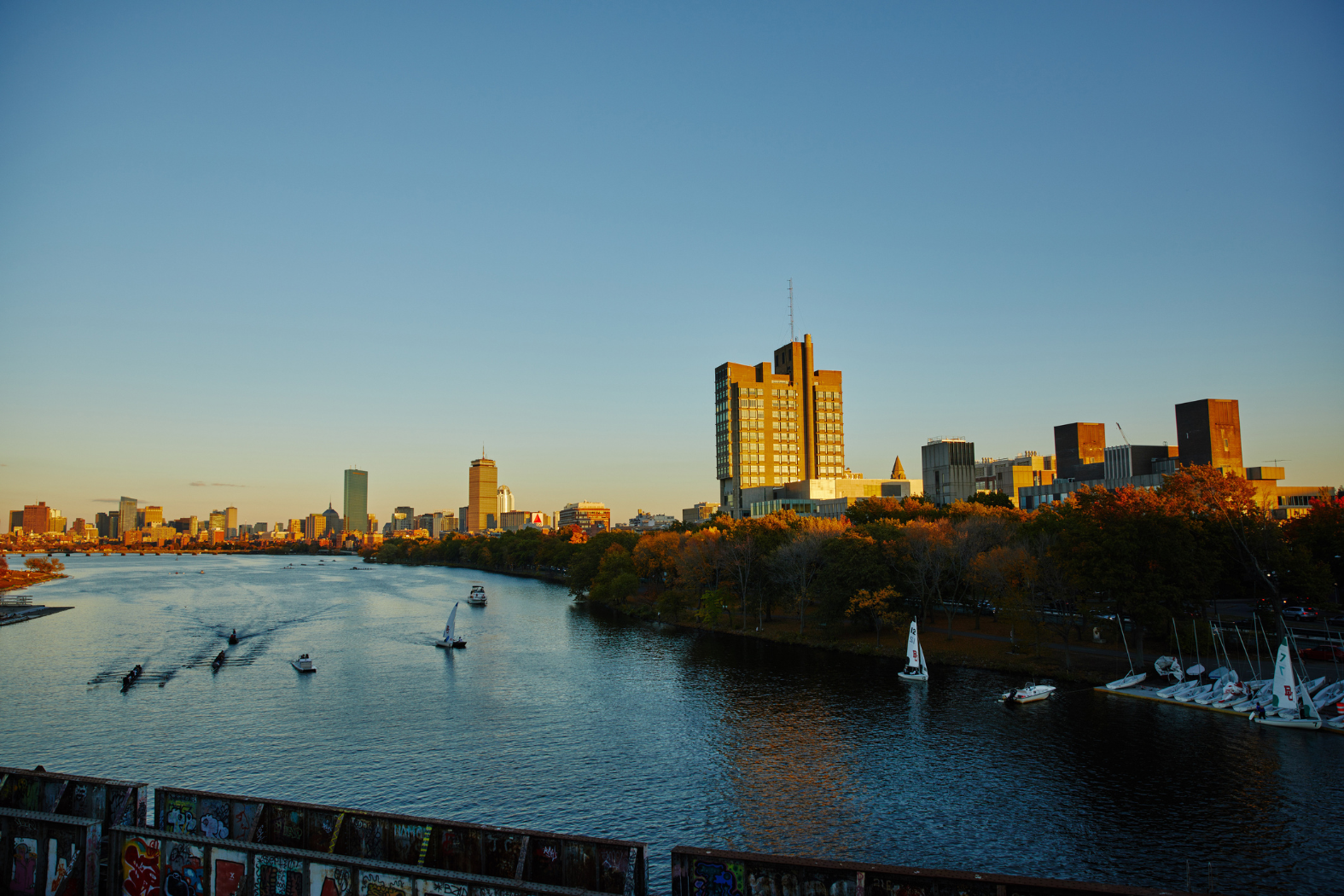 The carles river is in the foreground with University buildings and the Boston Skyline in the background.