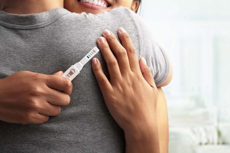 Couple hugging with pregnancy test