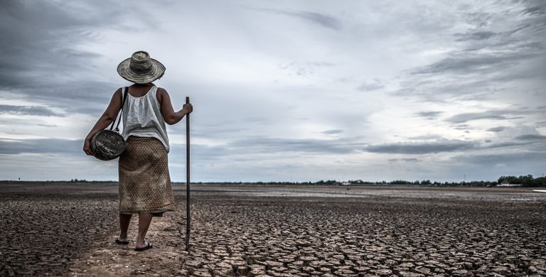 Woman standing on dry soil in fishing gear