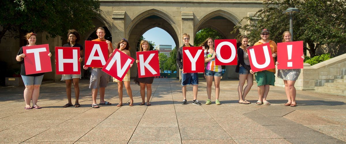 A group fo students holding out signs that spell out Thank You by the letter