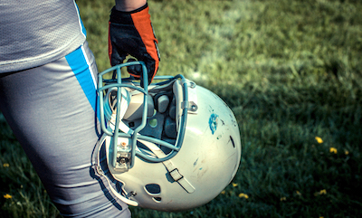 Scuffed football helmet hanging from player's hand