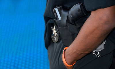Close-up on an African American police officer's arm and belt, with his gun in the middle of the image
