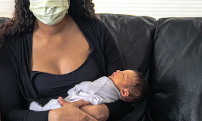 Woman wearing a mask and holding her newborn