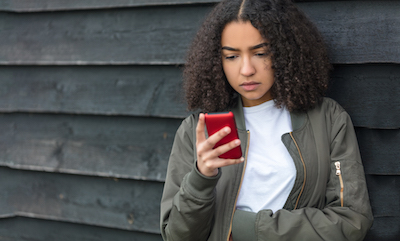 Teen looking at her phone with worried expression