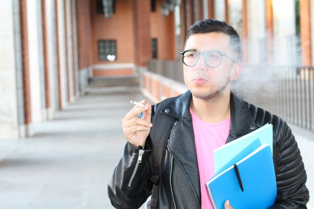 Ethnic student smoking on campus close up.