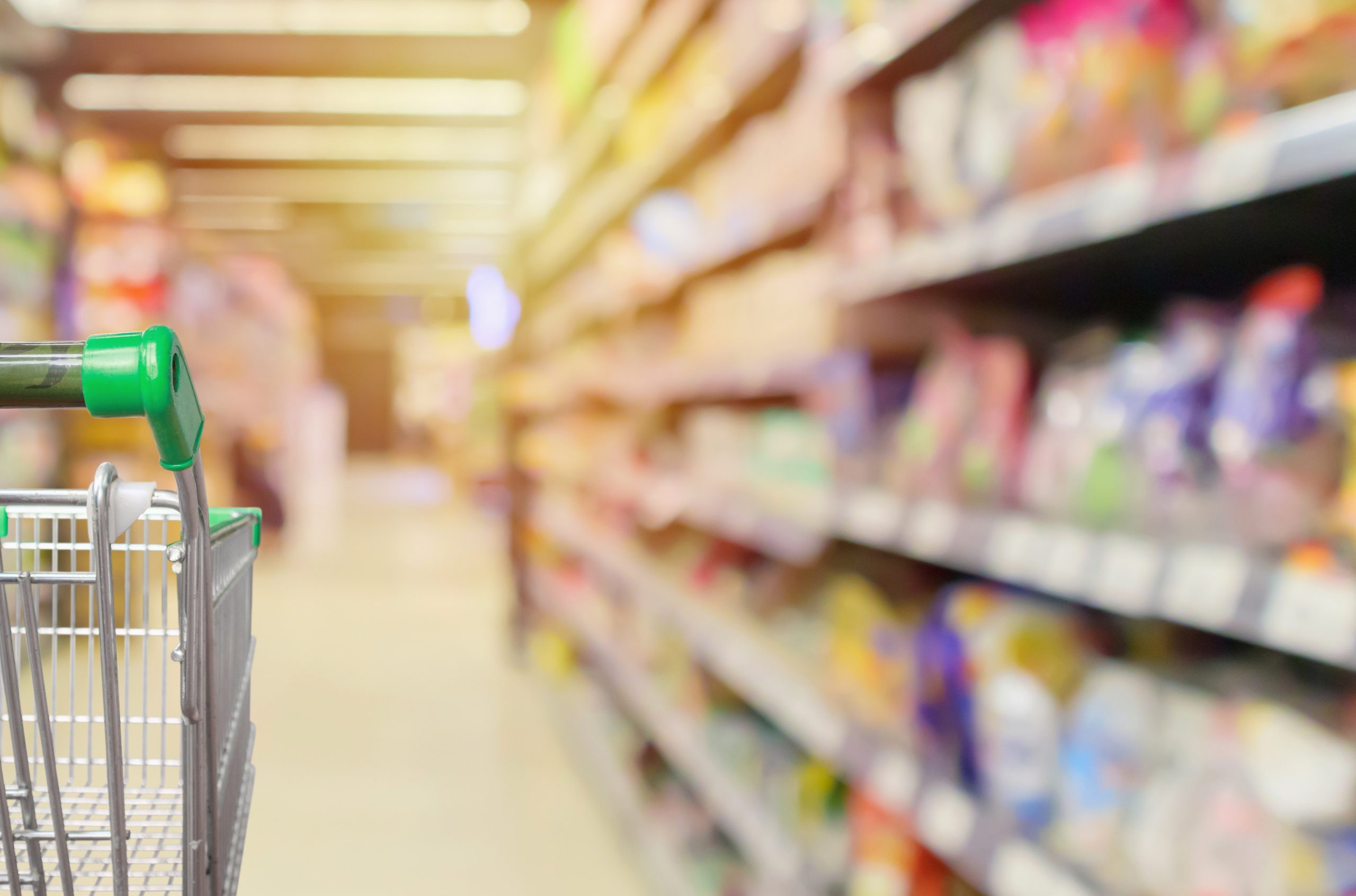 shopping cart in supermarket aisle with product shelves interior defocused blur background