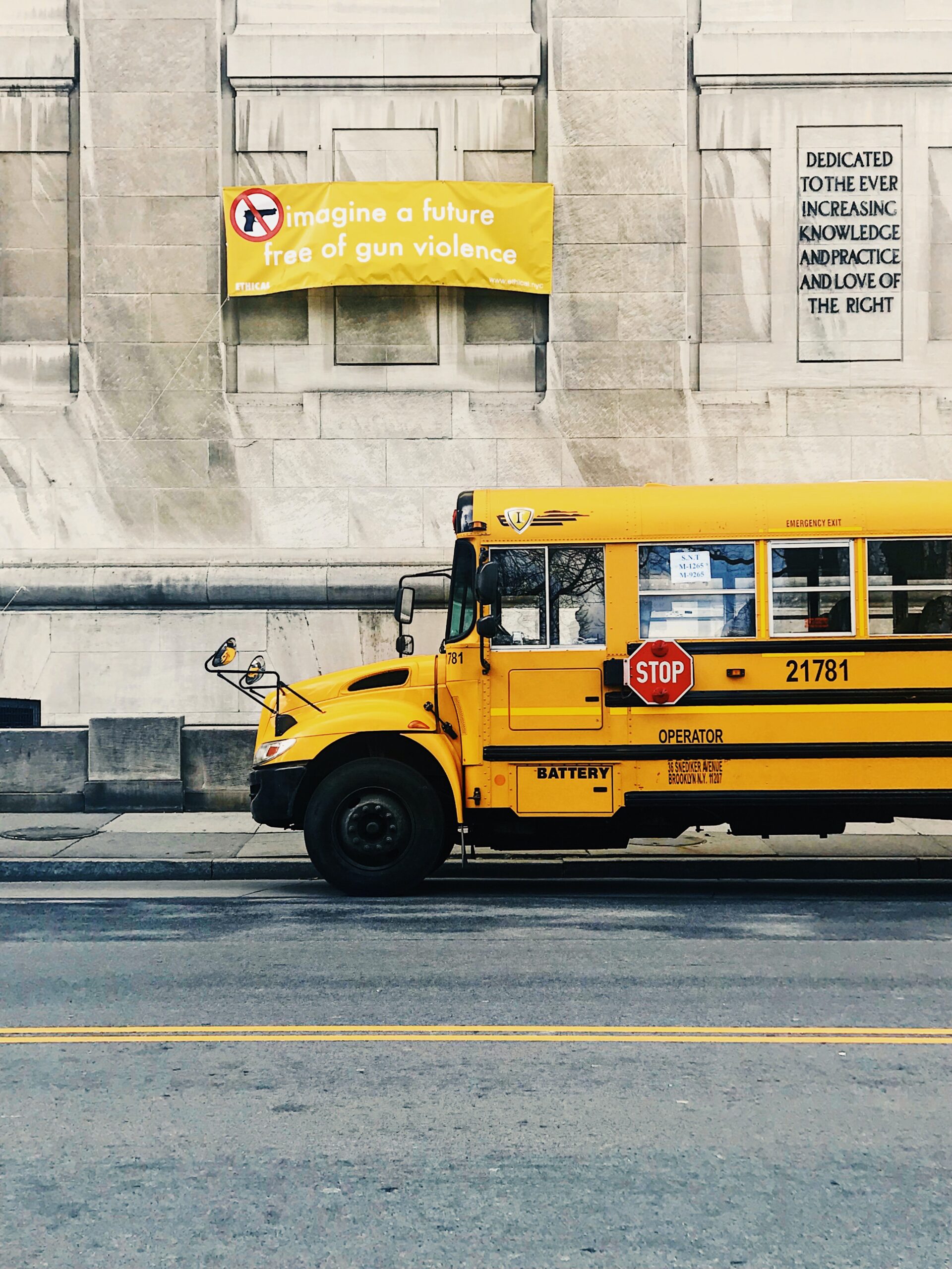 A school bus parked under a sign that reads "imagine a future free of gun violence"