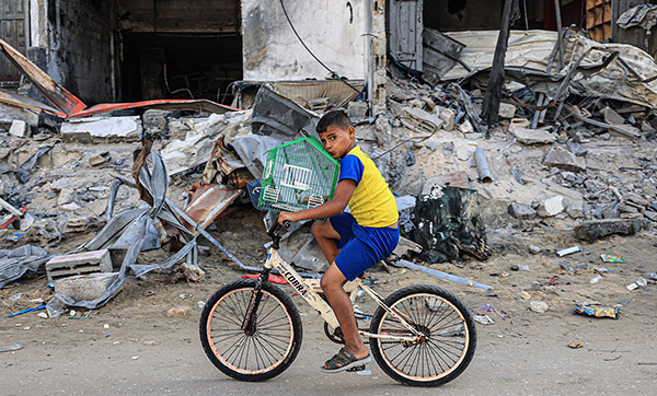 A Palestinian boy transports his bird on a bicycle past a destroyed building in Rafah in the southern Gaza Strip on November 6, 2023, amid the ongoing battles between Israel and the Palestinian group Hamas