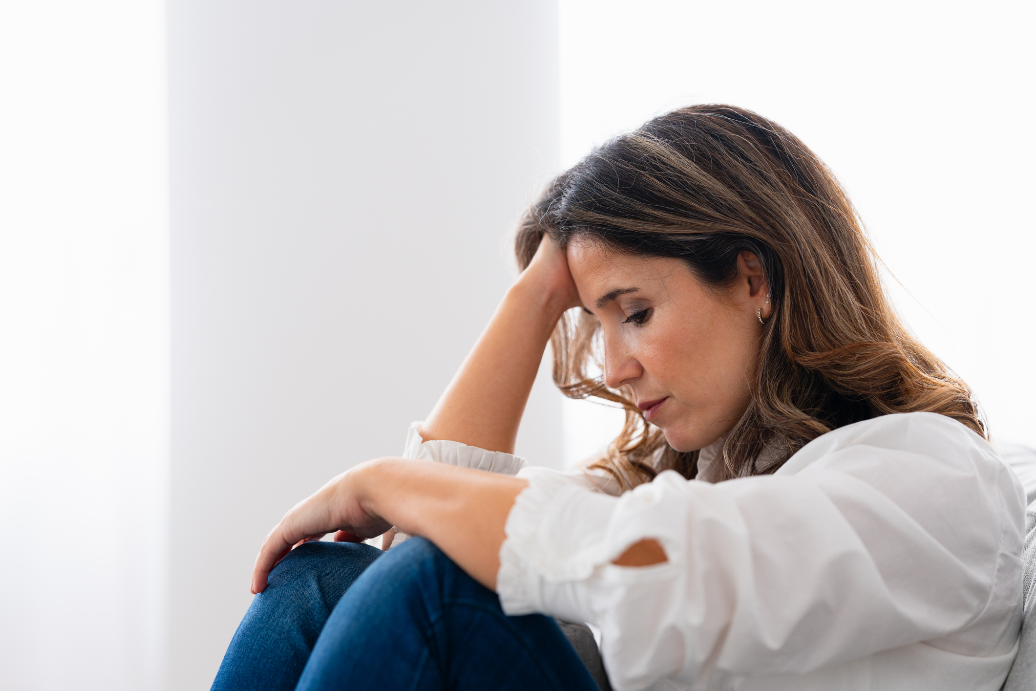 Close-up side view of a lonely woman sitting at home with sad look