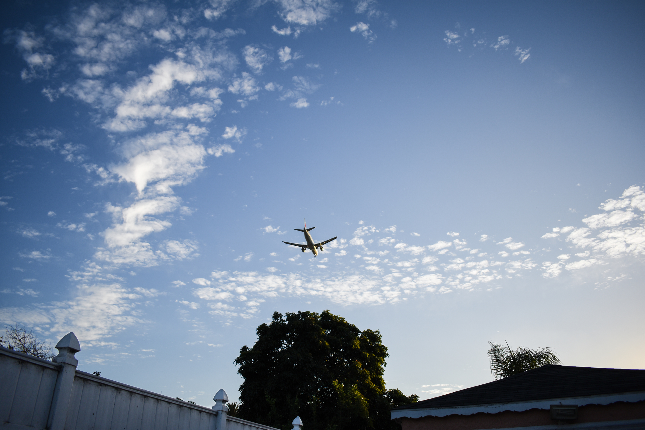 A commercial plane flying over a residential area in the afternoon