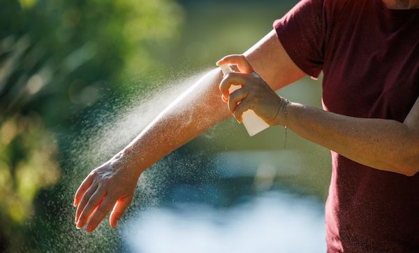 Woman applying insect repellent on her arm outdoors. Skin protection against tick and mosquito bite