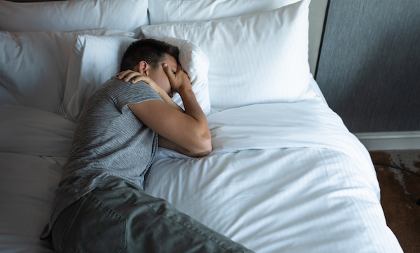 Lonely sad man lying in the bed.