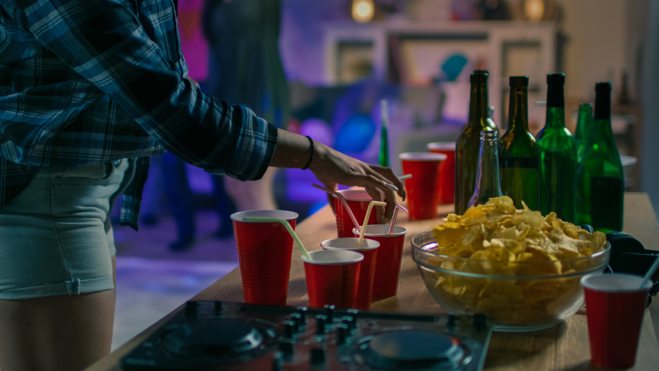 At the College House Party: Girl Takes Glass with Drink from the Tray. Diverse Group of Friends Have Fun, Dancing and Socializing. Disco Neon Strobe Lights Illuminating Room.