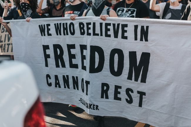 protesters-hold-banner-we-who-believe-in-freedom-cannot-rest