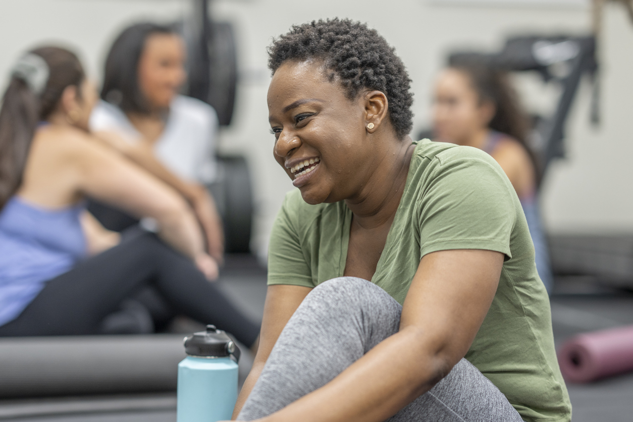 Black woman smiling with friends in yoga class