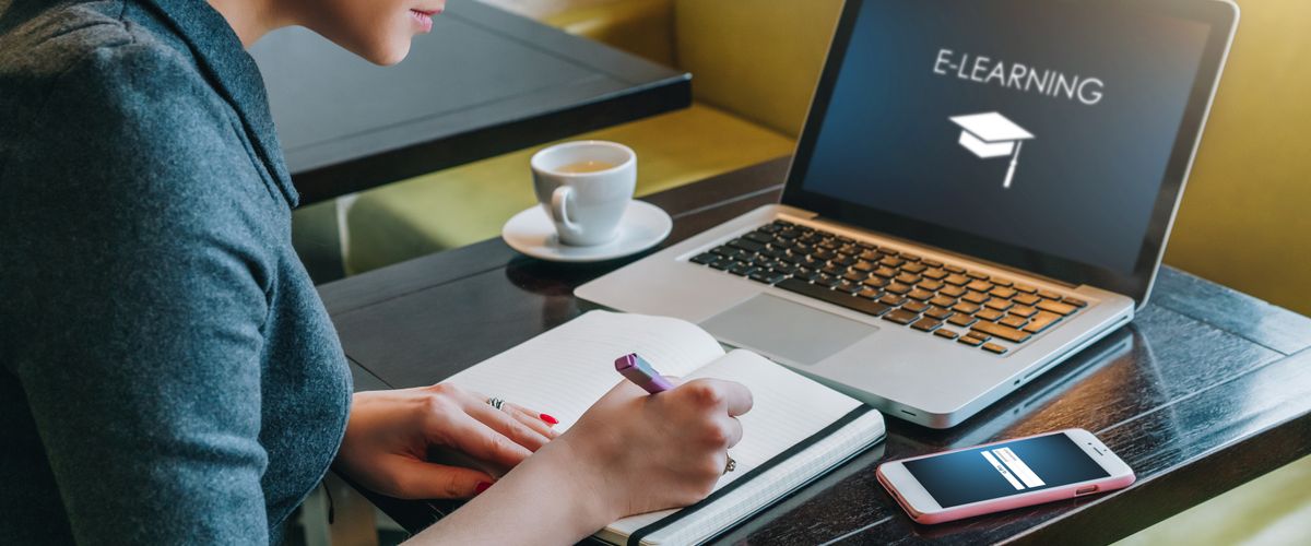 Person using a laptop and writing at the same time