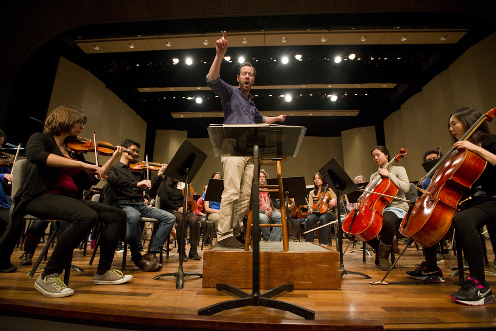 Conductor with student orchestra rehearsing