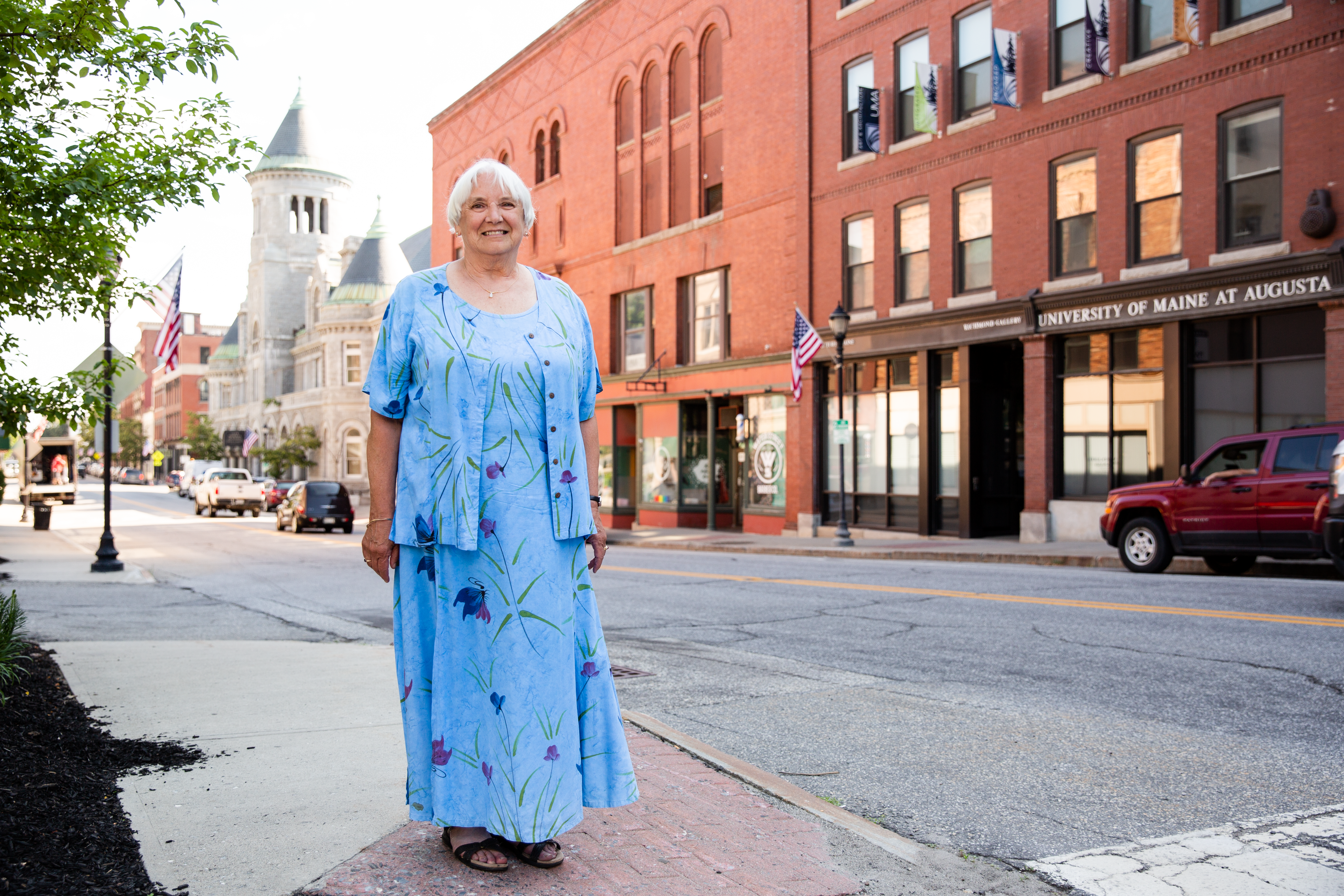 Older white haired women stand smiling on a class New England street