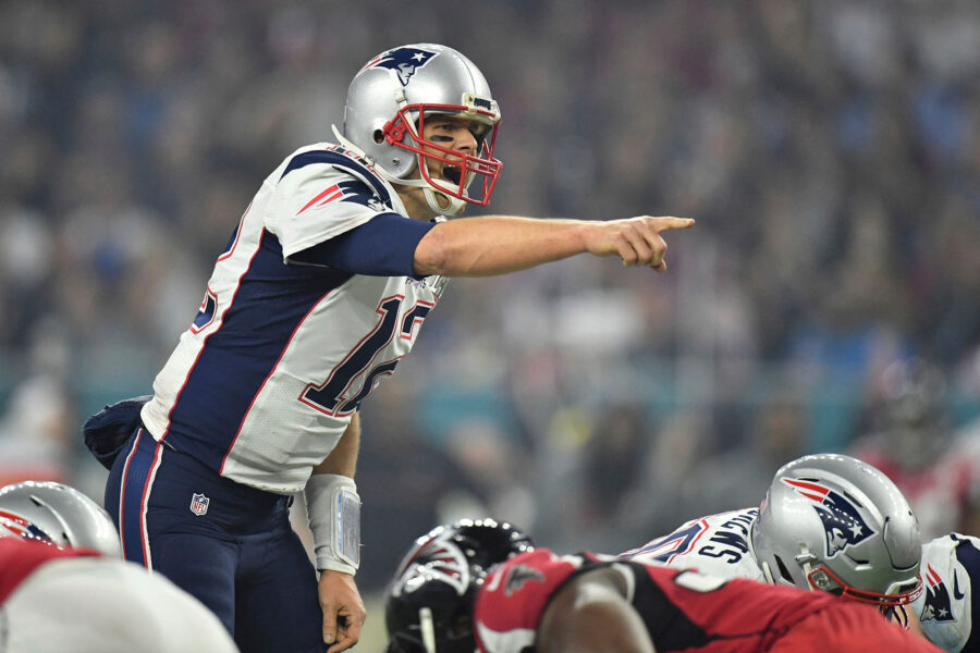 A photo of Tom Brady pointing at the rest of his team during a football game.