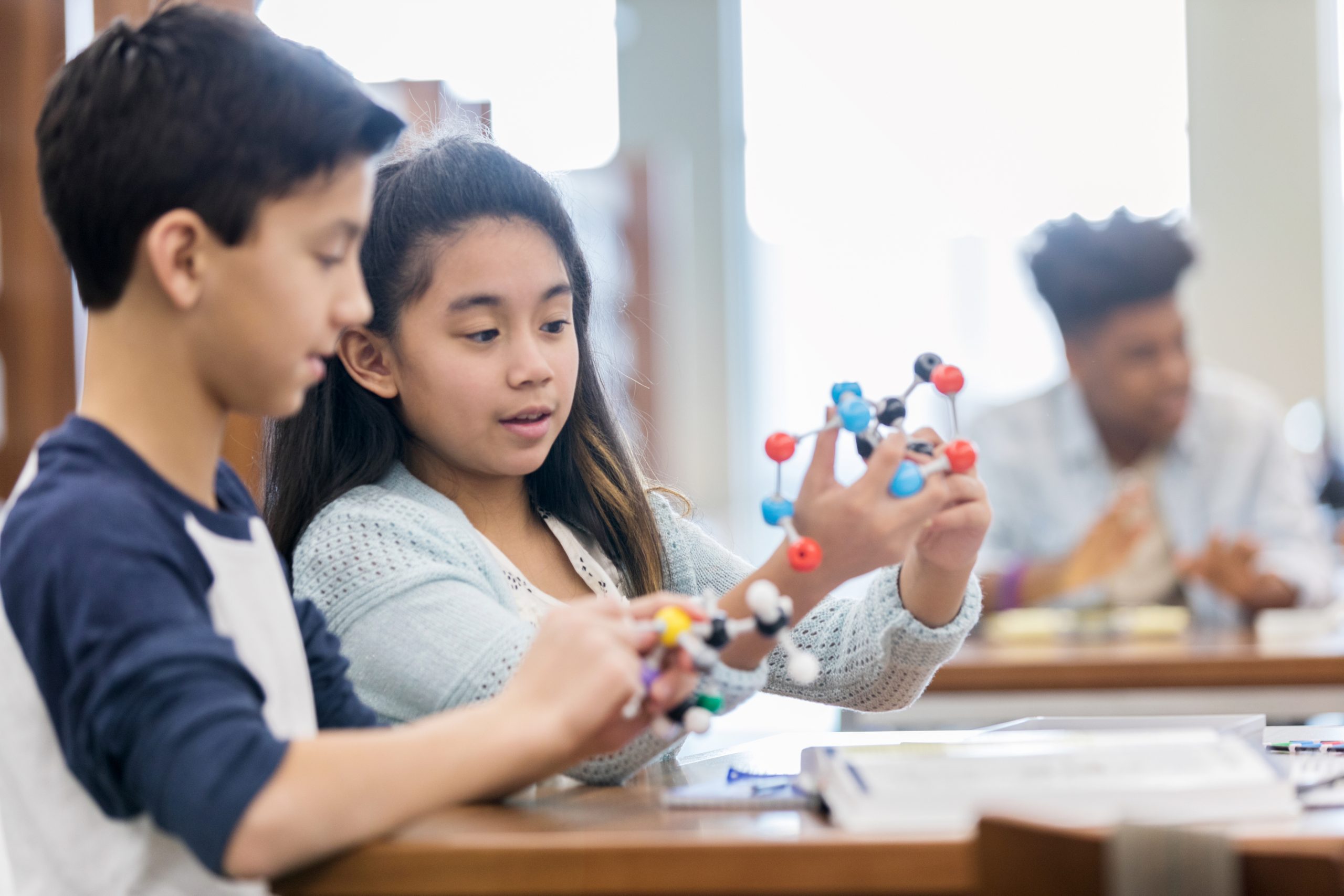 two latinx children holding molecule model