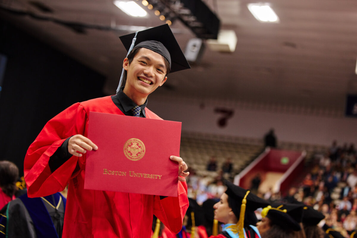 Undergraduate student smiling after he accepts his diploma