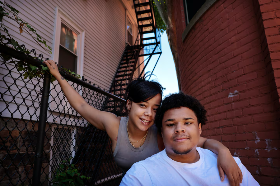 A photo of a brother and sister embracing each other outside their house.